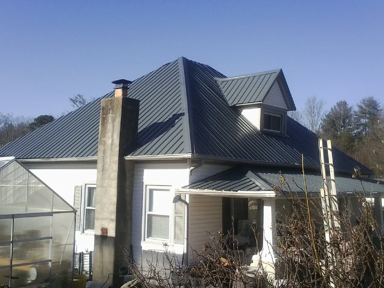 Dark blue standing seam metal roof on a white farmhouse with dormer — Slate & Tile Roof Repair by Roofing Brothers in Wolfe City