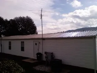 New metal roof on a single wide mobile home with a TV antenna in Wolfe City