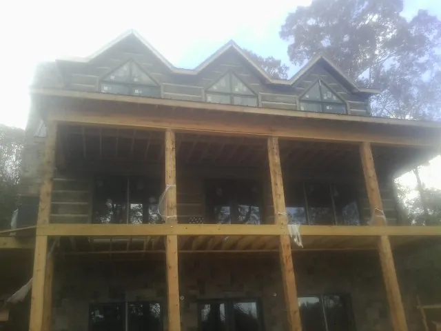 Dormers and porch framing on a large log home under construction — Roof Coating work by our crew in Wolfe City