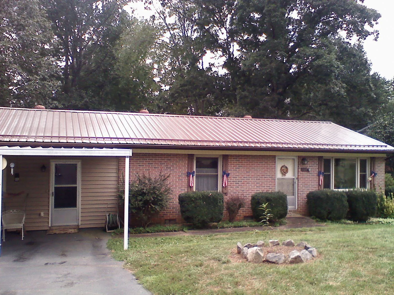 Bronze metal roof and carport on a brick ranch home — Roof Repair work by our crew in Wolfe City