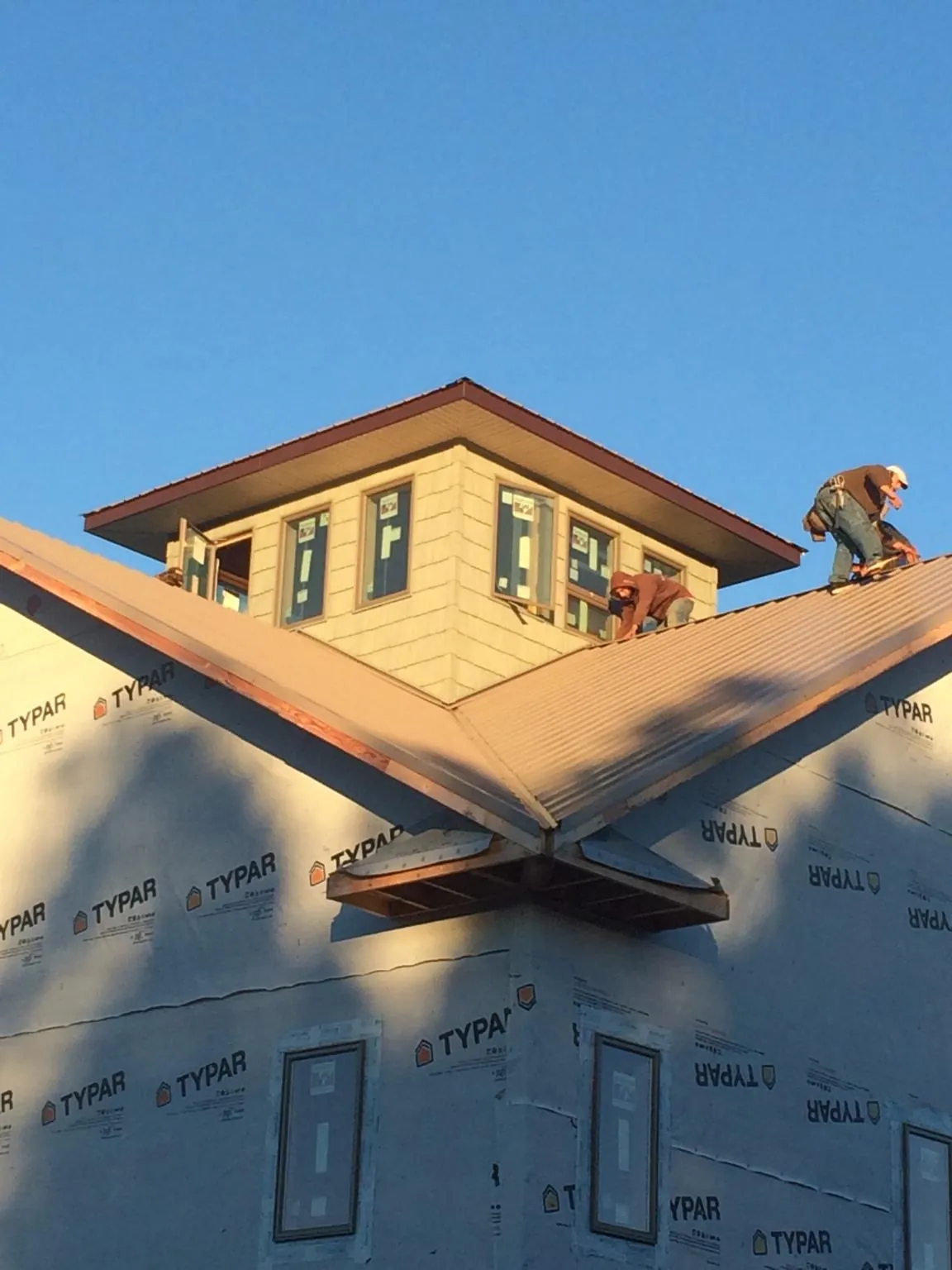 Roofers working around a rooftop cupola on a new metal roof at sunset — Roof Waterproofing in Wolfe City by Roofing Brothers